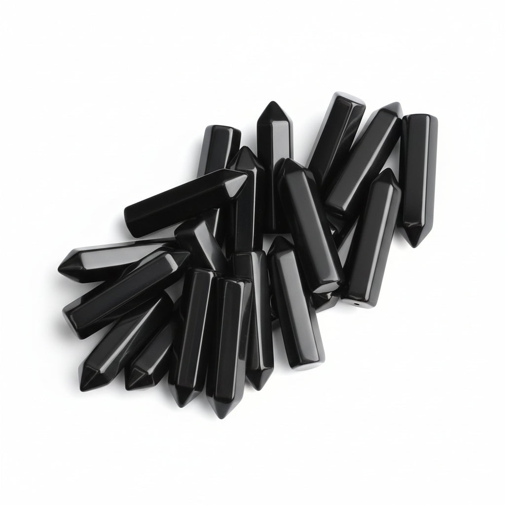 20 pieces of polished black obsidian crystal wands held in a hand, showing hexagonal points for healing and meditation.